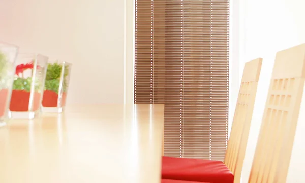 Innenjalousie vor einem Tisch mit Pflanzen und Sesseln im Wohnzimmer