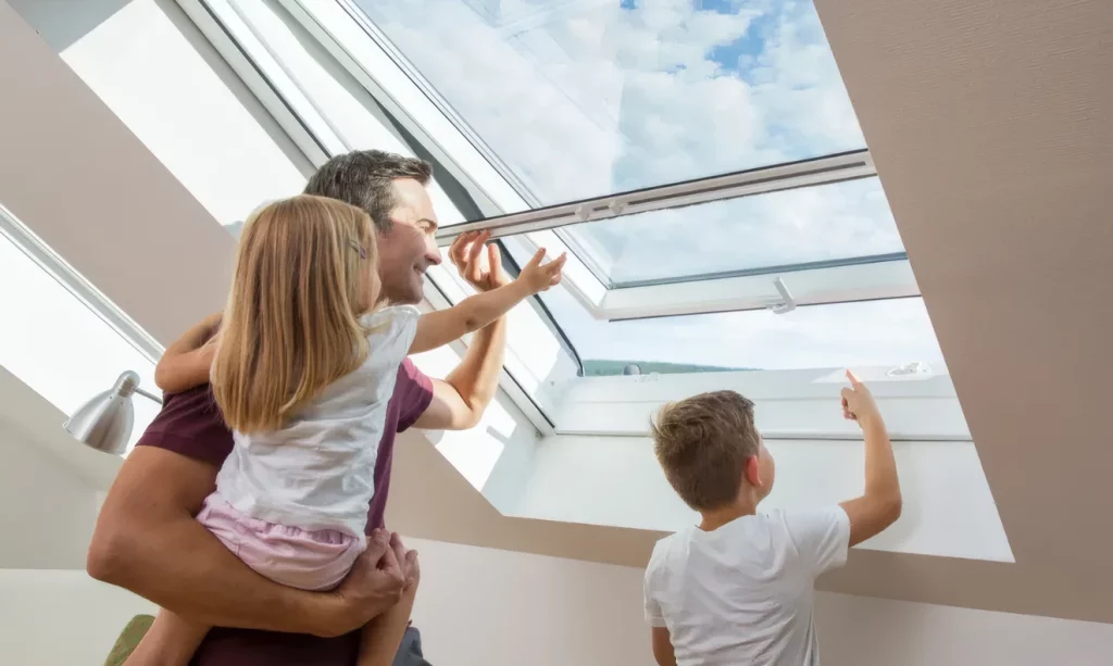 Ein Vater steht mit seinen Kindern vor einem Insektenschutzrollo montiert an einem Dachfenster